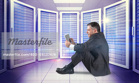 Mature businessman sitting using tablet against digitally generated server room with towers