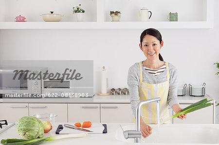 Woman washing green onions in an open kitchen