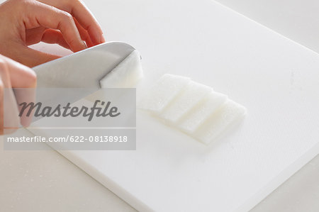 Close up of woman's hands cutting radish with a kitchen knife