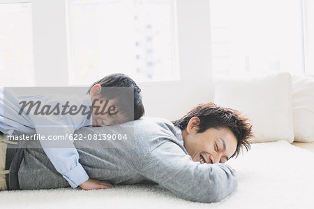 Young boy laying on his fathers back