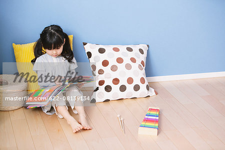 Elementary age girl reading an illustrated book on the floor of the kids room