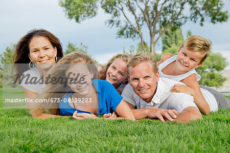 Portrait of a family of five in a dog pile near a lake