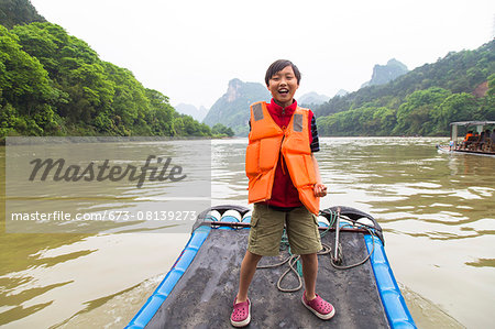 Boy standing on a bamboo raft on the Li River, Yangshuo, China