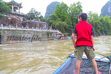 Boy standing on a bamboo raft on the Li River, Yangshuo, China