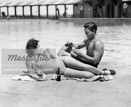 1930s 1940s COUPLE WEARING BATHING SUITS SITTING  RELAXING POOL SIDE DRINKING BEER