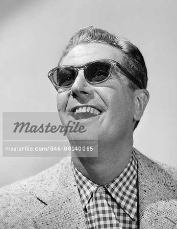 1950s MAN WEARING SUNGLASSES SMILING LOOKING UP