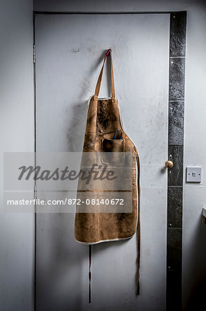 Leather workshop apron hanging on a workshop door.