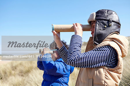 Two young boys on beach, looking through pretend binoculars