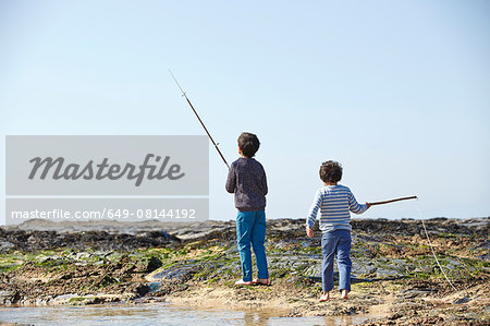 Two young boys, fishing on beach, rear view