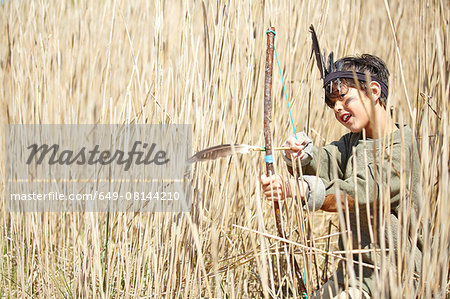 Young boy wearing fancy dress, holding home-made bow and arrow