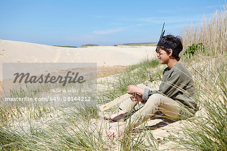 Young boy, wearing fancy dress, sitting on sand dunes