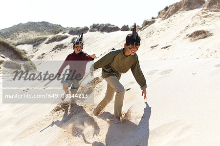 Two boys, wearing fancy dress, playing on sand