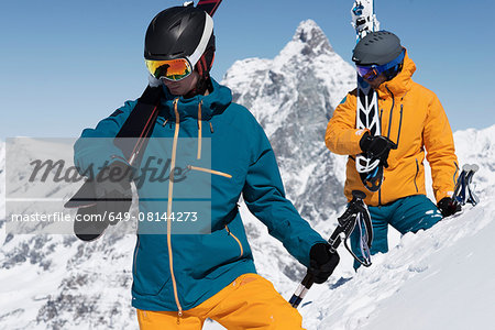 Two men carrying skis in snow, Zermatt, Valais, Switzerland