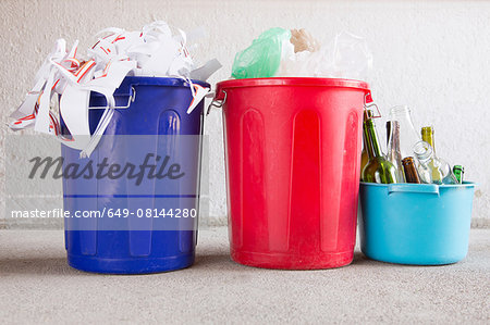 Three recycling buckets in garage with paper, bottles and plastic