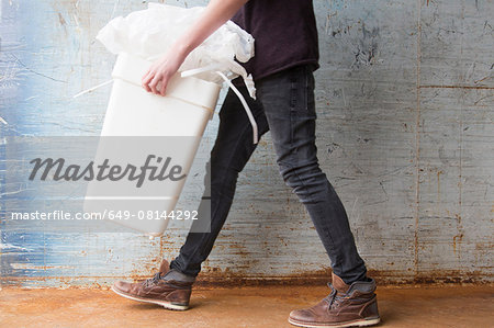 Teenage boy carrying bin with recyclable paper waste