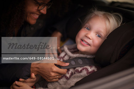 Mother adjusting son's seatbelt in car