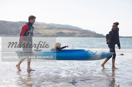 Parents carrying son in canoe on beach, Loch Eishort, Isle of Skye, Hebrides, Scotland