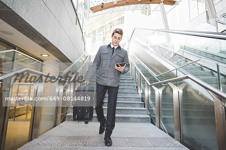 Portrait of young businessman commuter using digital tablet.