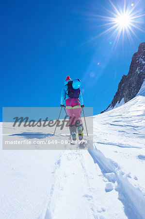 Rear view of mature female skier moving up Mont Blanc massif, Graian Alps, France