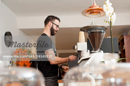 Cafe waiter preparing fresh coffee behind counter