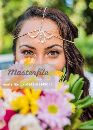 Close up portrait of bride behind colorful boquet at Hawaiian wedding, Kaaawa, Oahu, Hawaii, USA