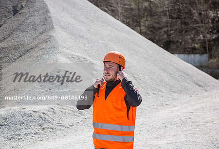 Quarry worker fastening helmet at gravel quarry