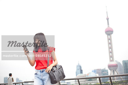 Young businesswoman, using smartphone, outdoors, Shanghai, China