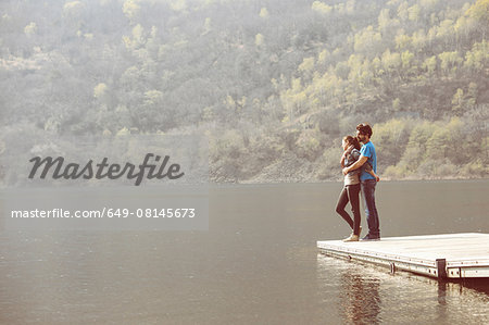 Young couple looking out from pier at Lake Mergozzo, Verbania, Piemonte, Italy