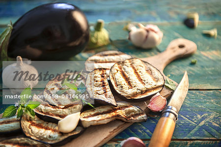 Grilled aubergine slices, garlic and peppermint on a rustic wooden table