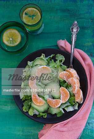 A mixed leaf salad with avocado and clementines