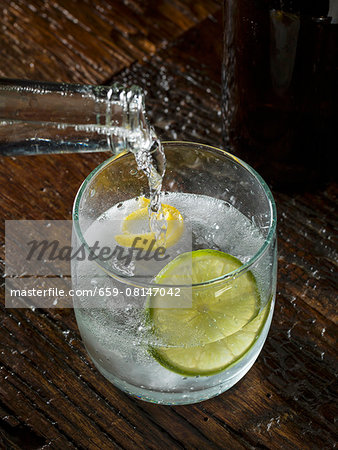 Tonic water being poured into a glass of gin