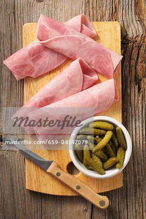 Rolled ham and gherkins on a chopping board