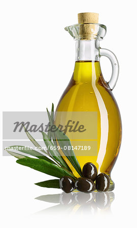 A carafe of olive oil, a sprig of olive leaves and black olives