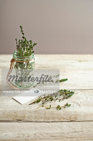 A jar of thyme herb on a light wooden surface