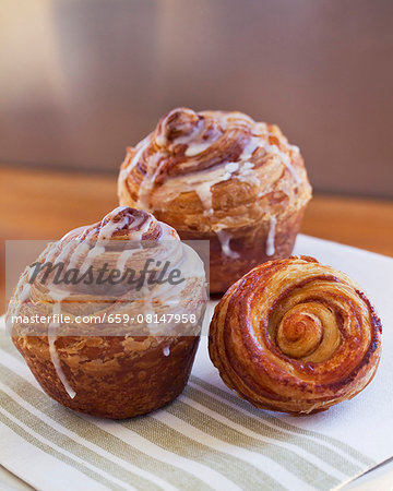 Three cinnamon buns with icing sugar on a napkin