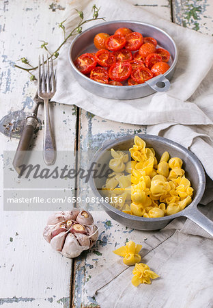 Sacchettini with baked tomatoes and garlic on an old wooden table