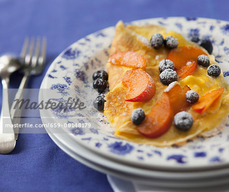 Sweet omelette with blueberries, peaches and icing sugar