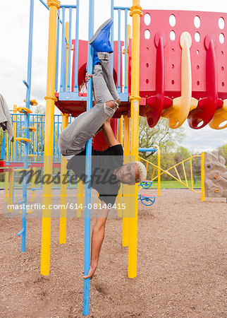 Young man upside down on pole in playground