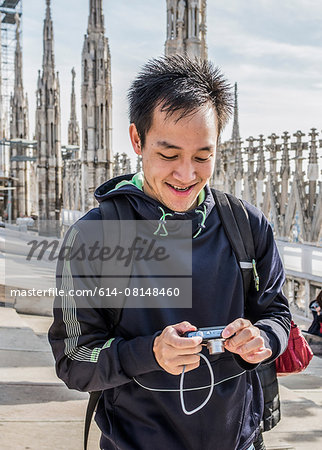Young man standing on roof of Duomo Cathedral, Milan, Italy