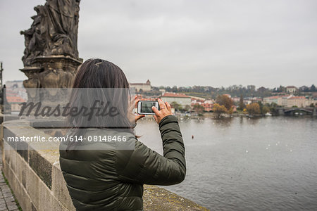 Rear view of woman using smartphone on Charles Bridge, Prague