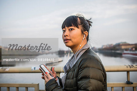 Portrait of woman in front of river wearing earphones