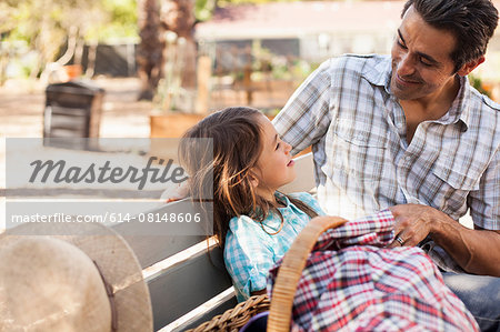 Mid adult man talking with daughter on community garden bench