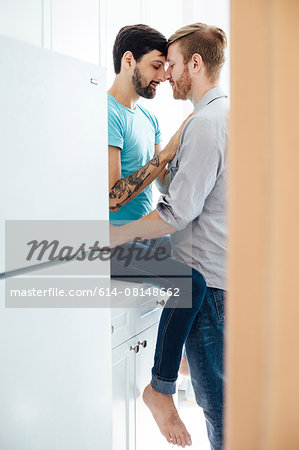 Male couple in kitchen, face to face, embracing