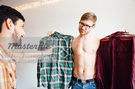 Male couple, mid adult man asking for help choosing shirt