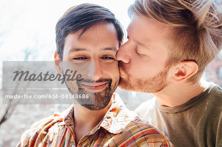 Portrait of male couple, mid adult man kissing his partner's cheek