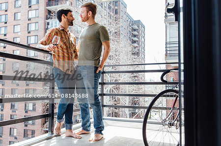 Male couple standing on balcony, face to face