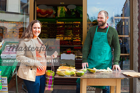 Customer and grocer in front of greengrocer's shop