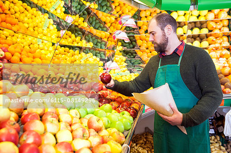 Grocer looking at fruit in greengrocer's shop