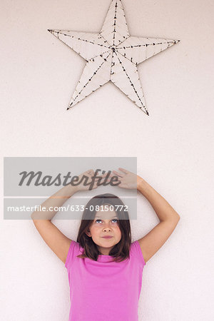 Girl standing beneath star decoration, daydreaming, portrait