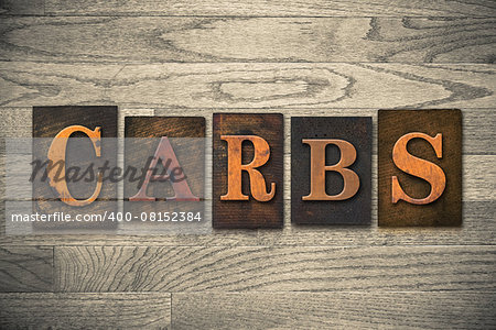 The word "CARBS" theme written in vintage, ink stained, wooden letterpress type on a wood grained background.